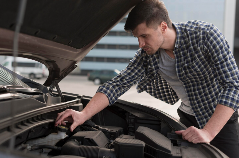 Cheap car maintenance tips with car owner checking engine oil under the hood at home.